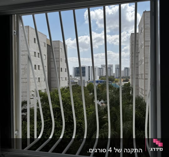 סורגים בחלון עם נוף לבניינים ועצים
